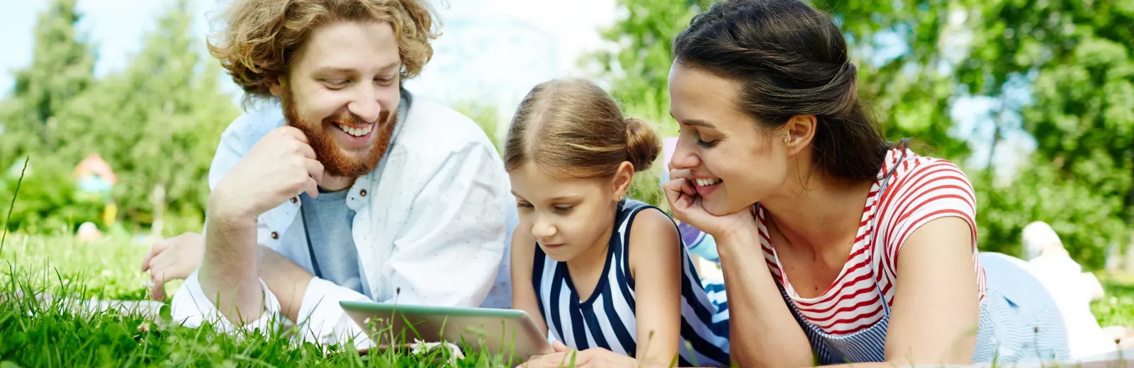 Family laying and reading in green grass